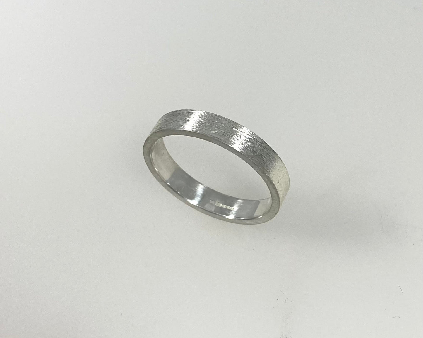 Simple bark texture 4mm wide flat ring with hidden ashes inside shank .
