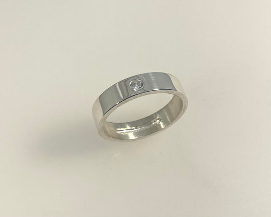 Single Brilliant cut stone set in rub over 5mm wide flat ring with hidden ashes inside shank