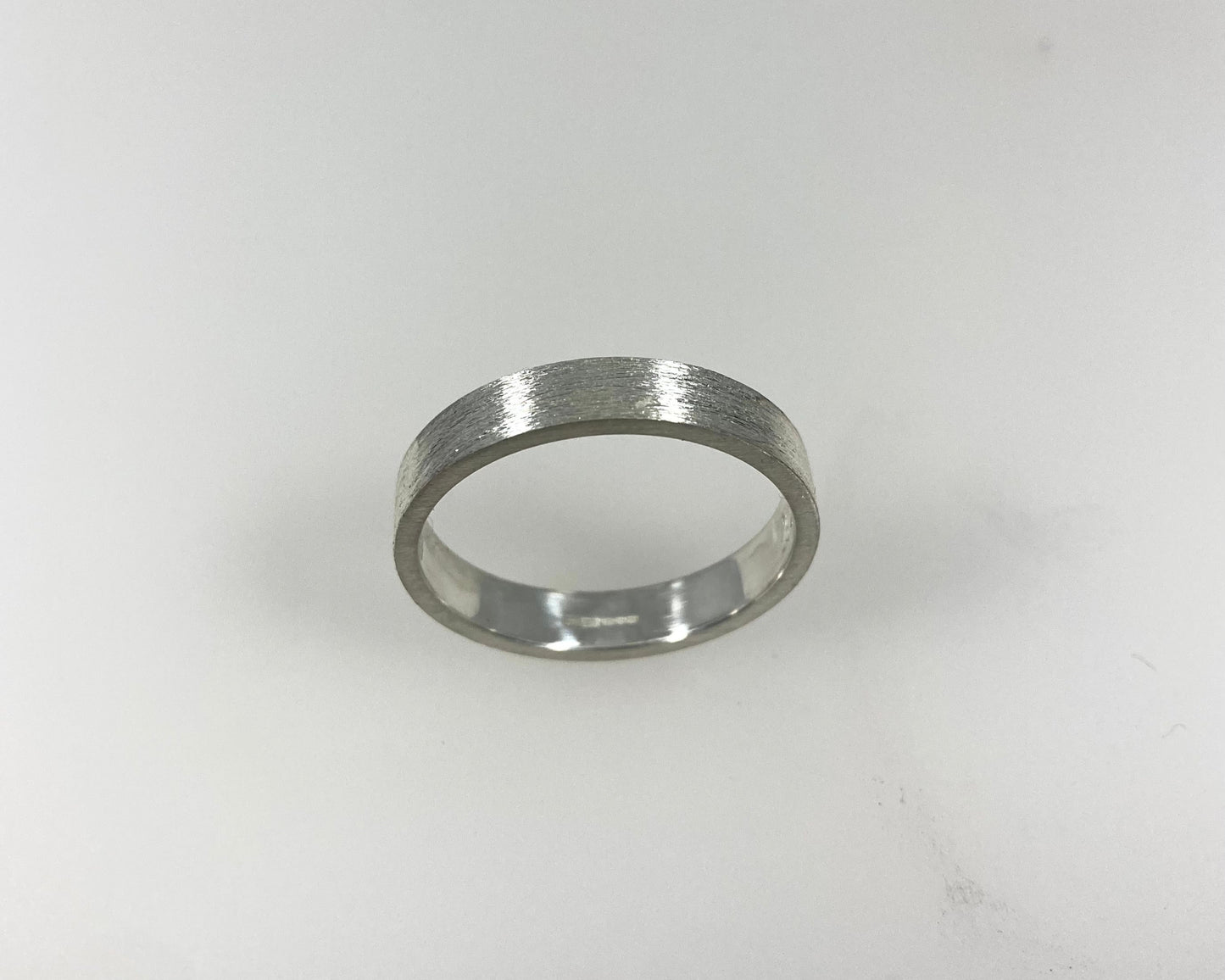 Simple bark texture 4mm wide flat ring with hidden ashes inside shank .