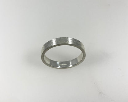 Simple bark texture 4mm wide flat ring with hidden ashes inside shank .
