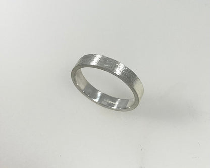 Simple bark texture 4mm wide flat ring with hidden ashes inside shank .