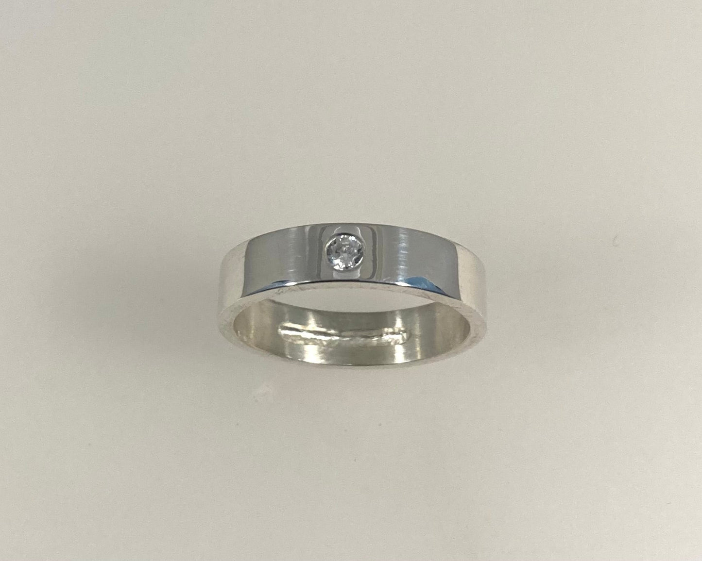 Single Brilliant cut stone set in rub over 5mm wide flat ring with hidden ashes inside shank