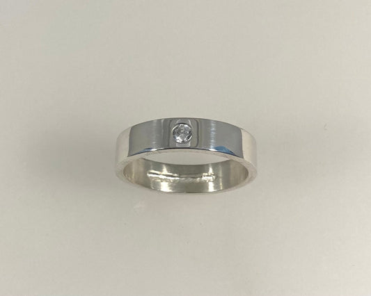 Single Brilliant cut stone set in rub over 5mm wide flat ring with hidden ashes inside shank